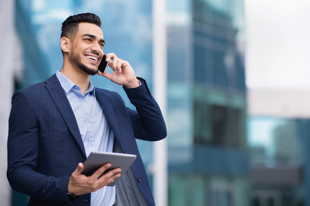 A man in a suit and tie is engaged in a phone conversation, looking focused and professional.