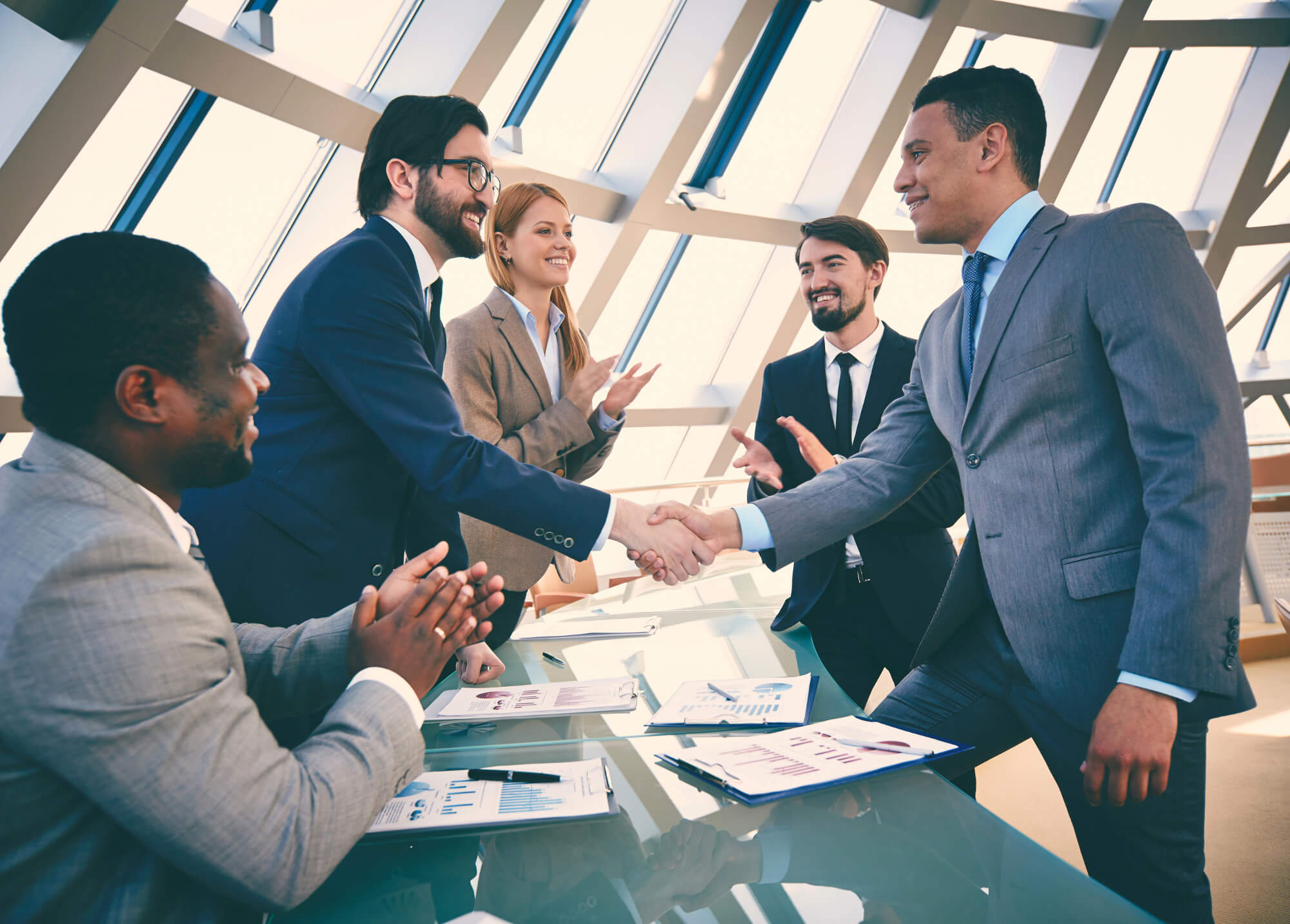 Business professionals shaking hands during a meeting, symbolizing agreement and collaboration.
