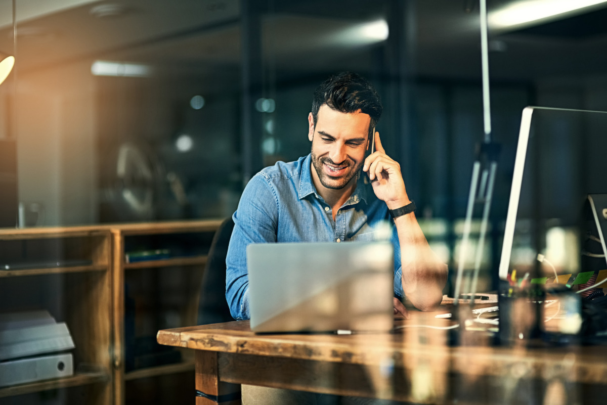 Man talking on phone and working on laptop